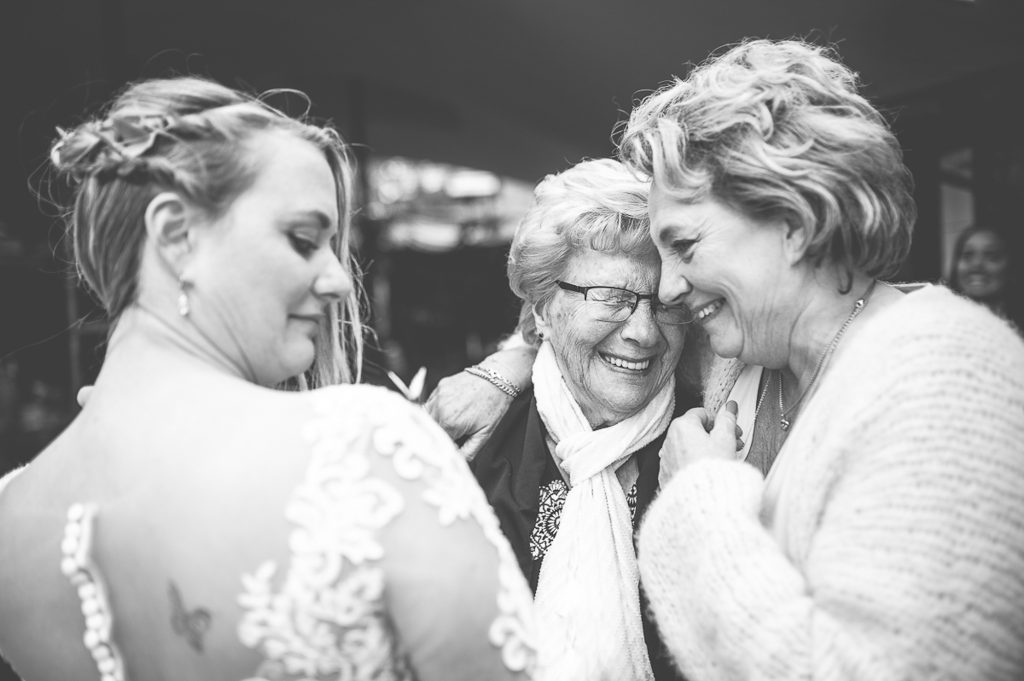 Oma lacht tranen van geluk bij het zien van haar kleindochter in bruidsjurk.