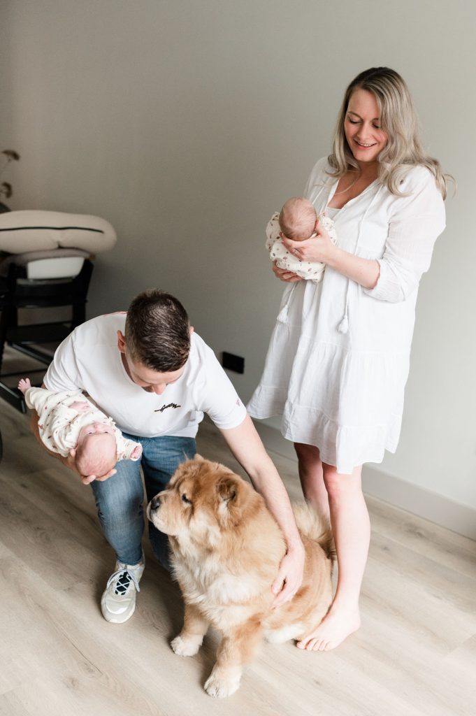 Ouders met tweeling op de arm, knuffelen hond.
