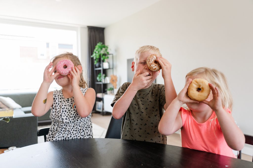 Drie kinderen die door een donut kijken met hun ogen.