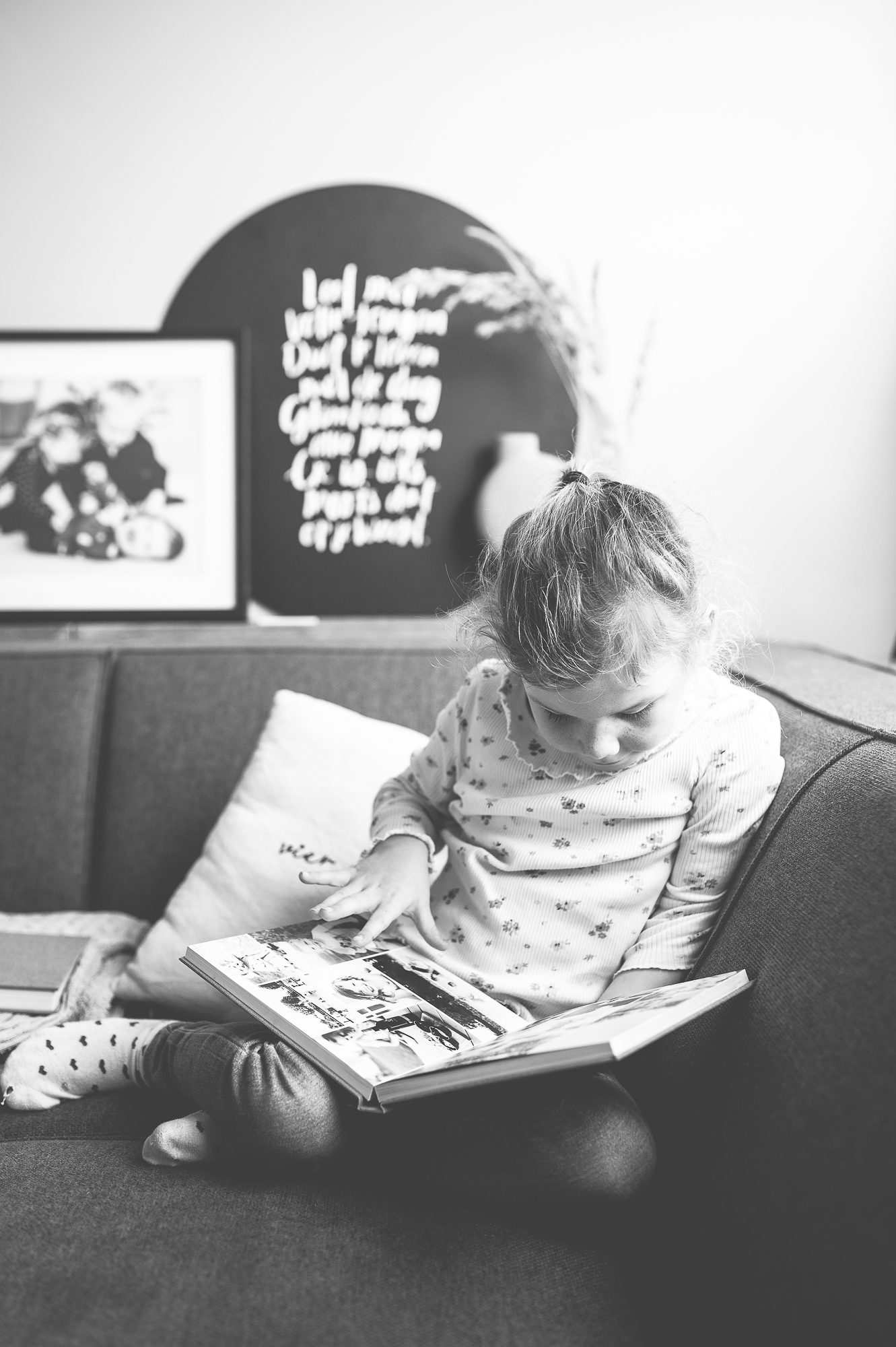 Meisje van 7 jaar die op de bank rustig kijkt naar de fotoboeken van het gezin.
