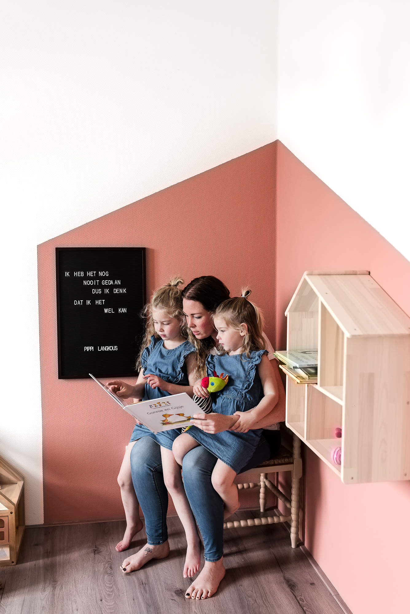 Moeder die haar twee dochters voorleest uit een boek in een schattig kinder hoekje.