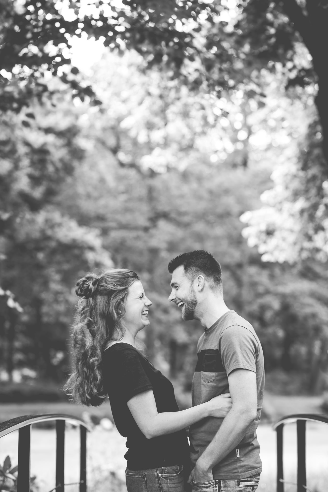 verloving-fotoshoot-bos Verliefd en verloofd koppel die geniet van een moment samen, elkaar verliefd in de ogen kijken.