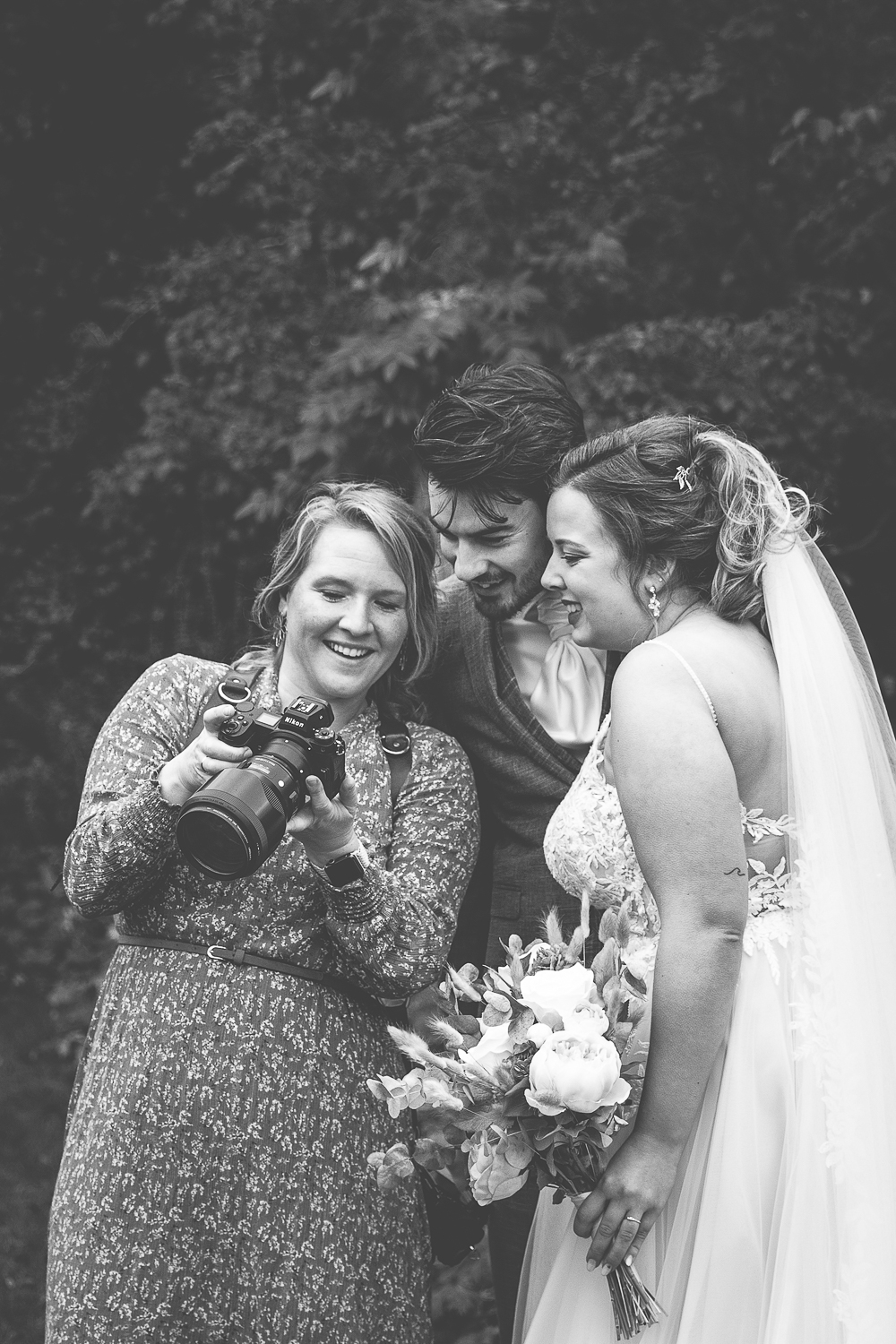 Bruidsfotograaf toon een gemaakte foto aan het bruidspaar, ze glimlachen en genieten.
