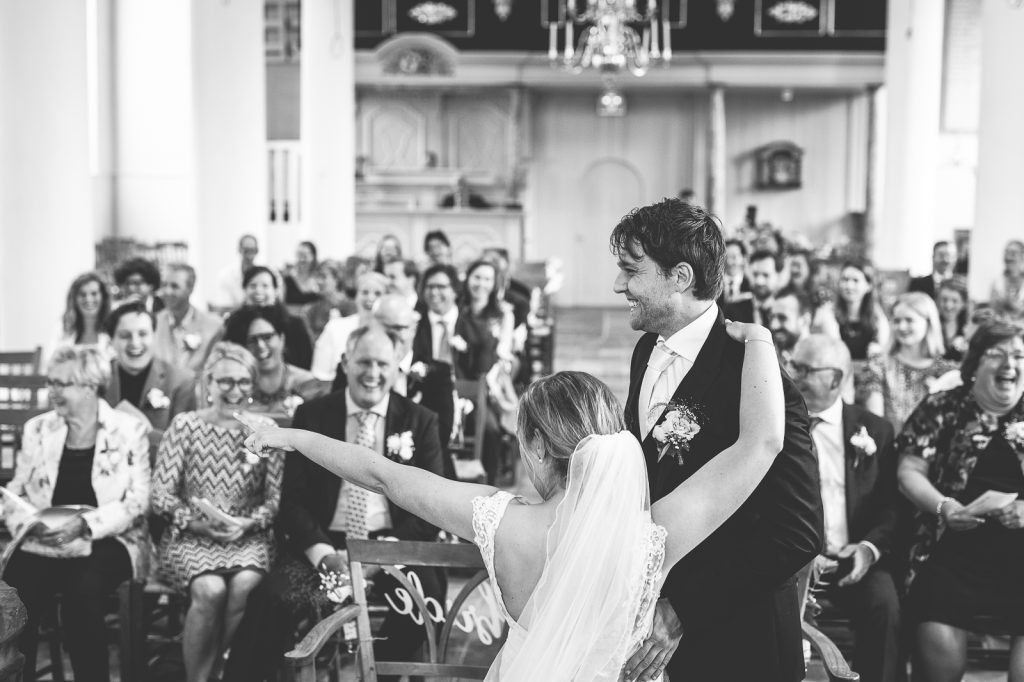Bruidspaar in kerk tijdens hun huwelijksdienst, ze lachen en genieten.