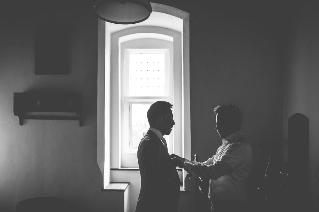 bruidegom wordt door vriend geholpen bij klaarmaken, er is mooi tegenlicht in kasteel