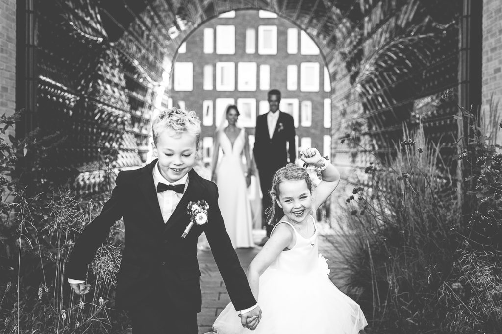 Bruidskinderen rennen lachend weg van hun ouders die net getrouwd zijn.