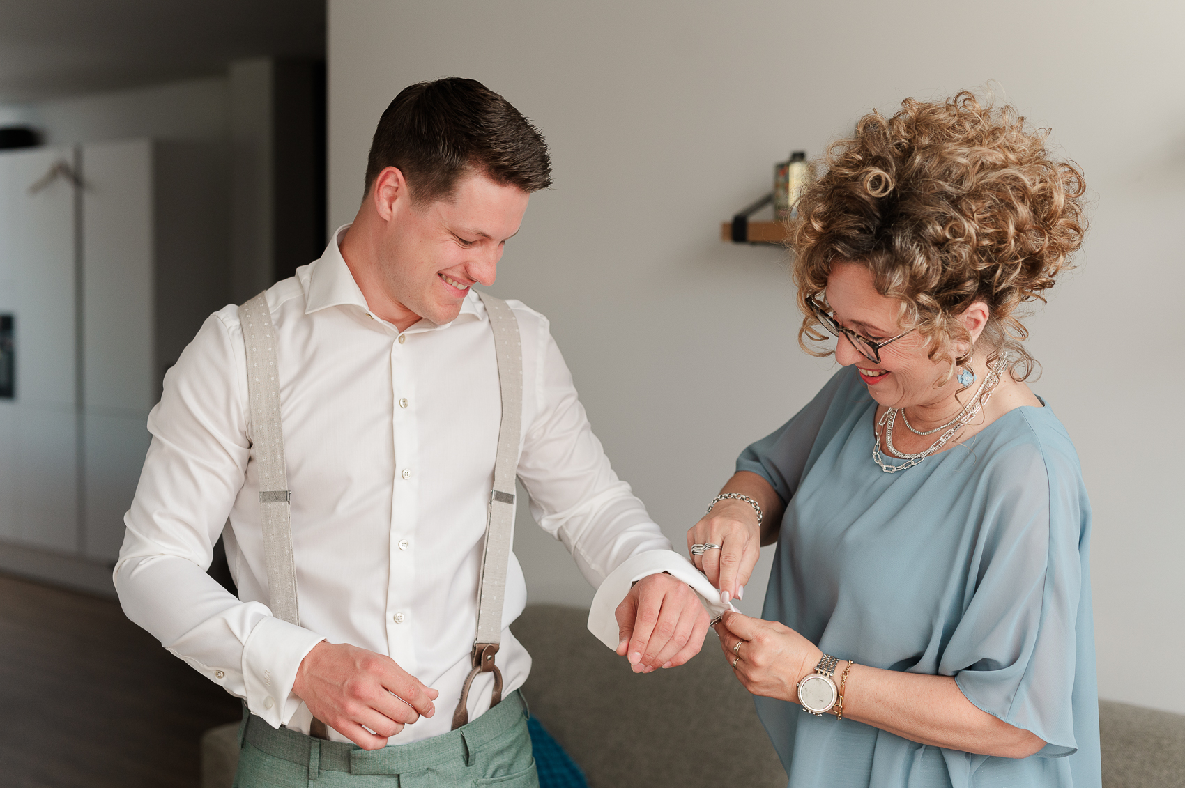 Bruidegom met zijn moeder die hem helpt tijdens de aankleding op de bruiloft.