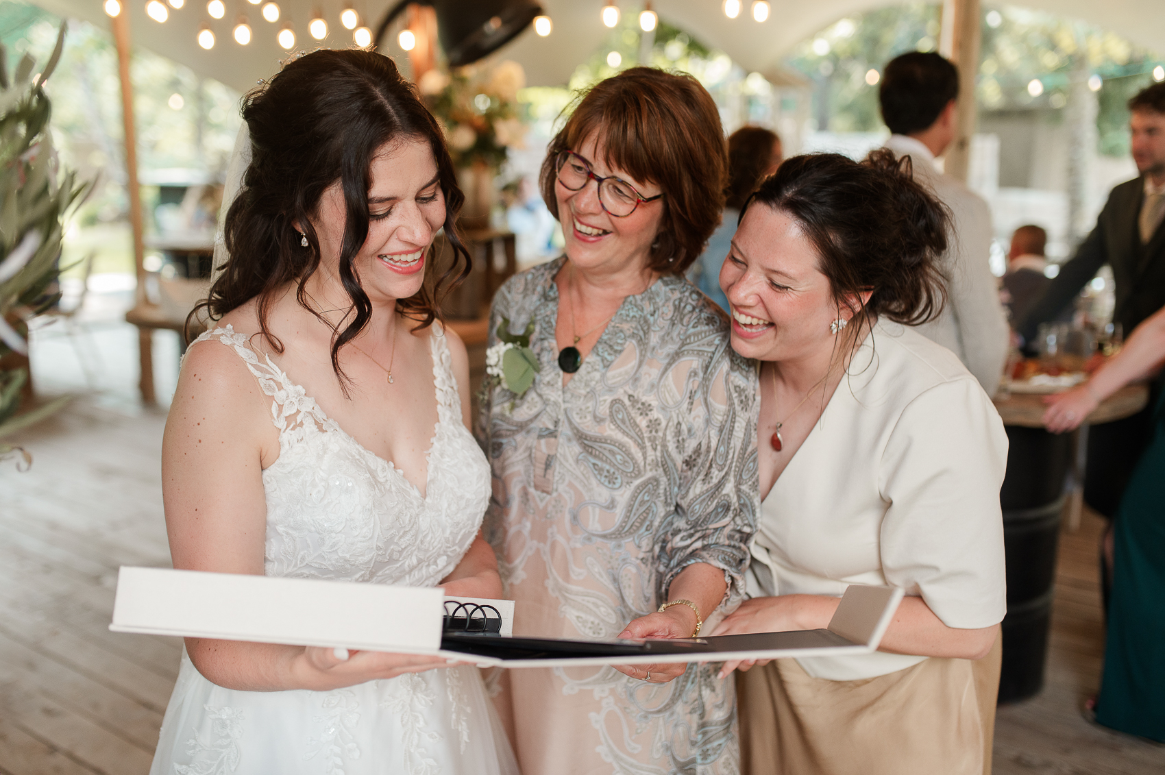 cadeaus worden in ontvangst genomen tijdens de receptie borrel van een bruiloft. ik zie 3 genietende vrouwen, kijken in een fotoboek.